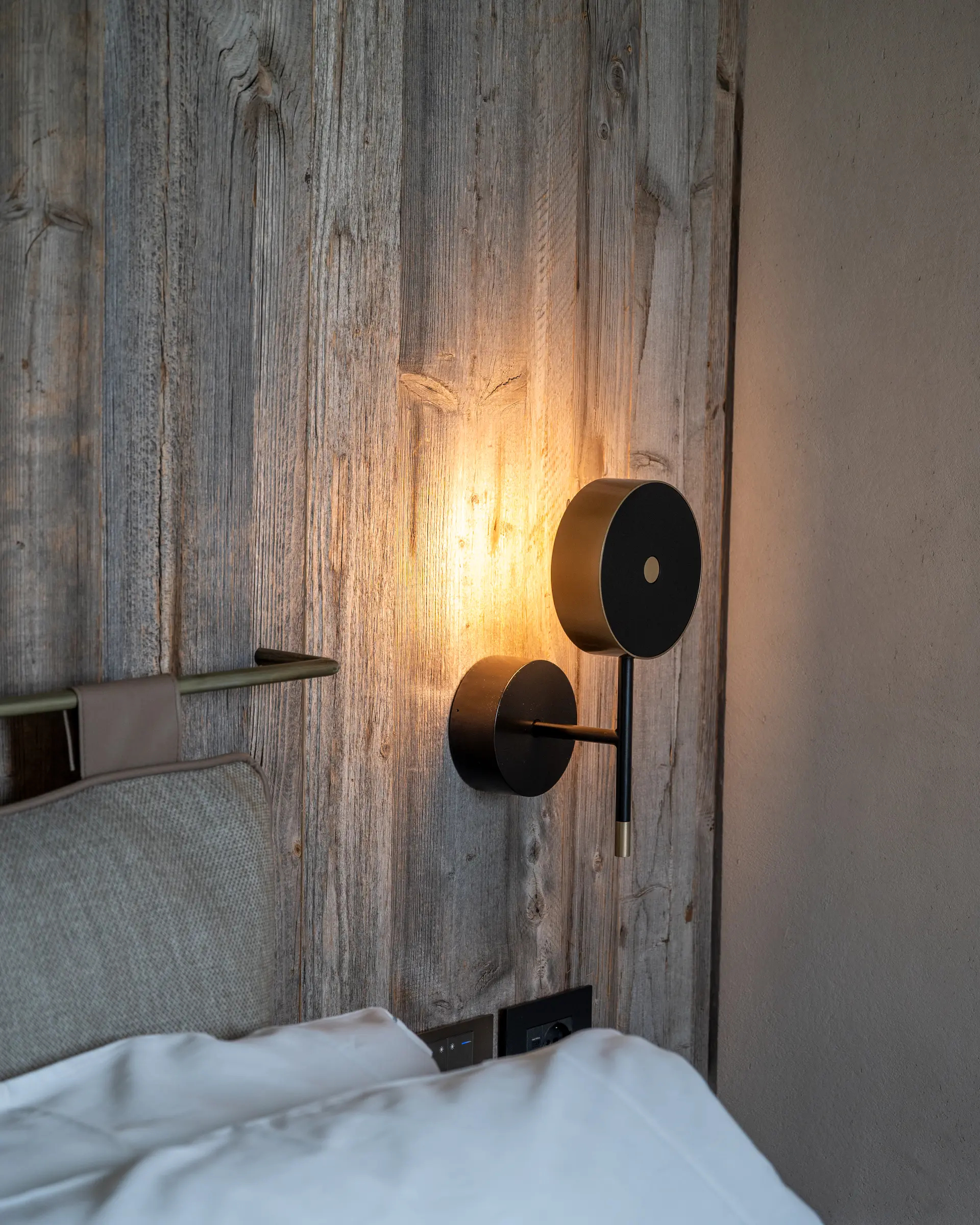 Suite — brushed-brass and iron sconce on ancient-wood panelling at Borgo Taurino
